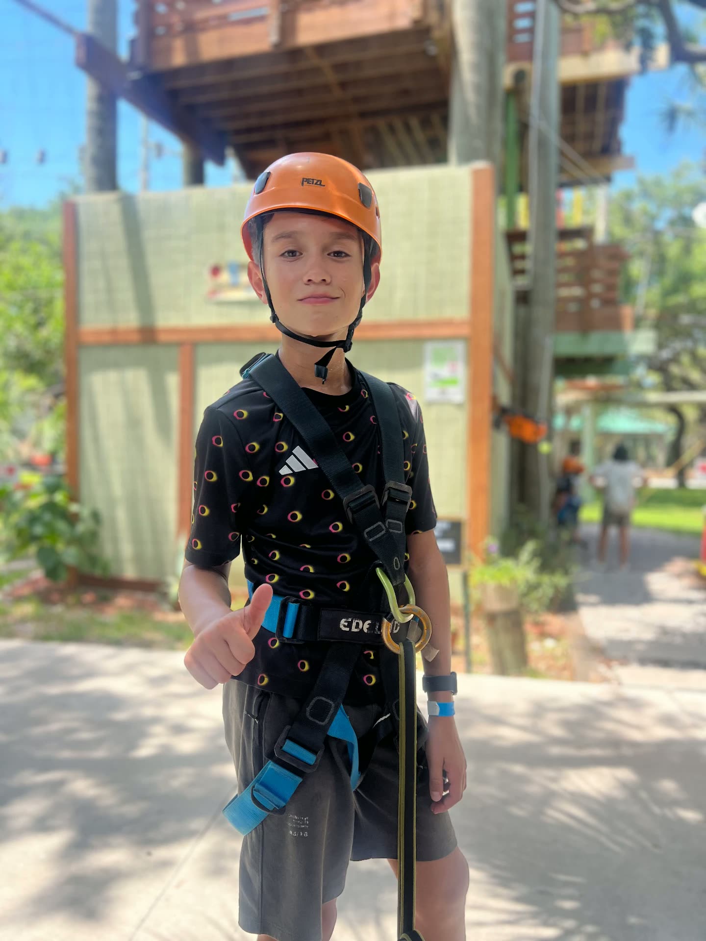 A child in a helmet and climbing harness at an outdoor ropes course