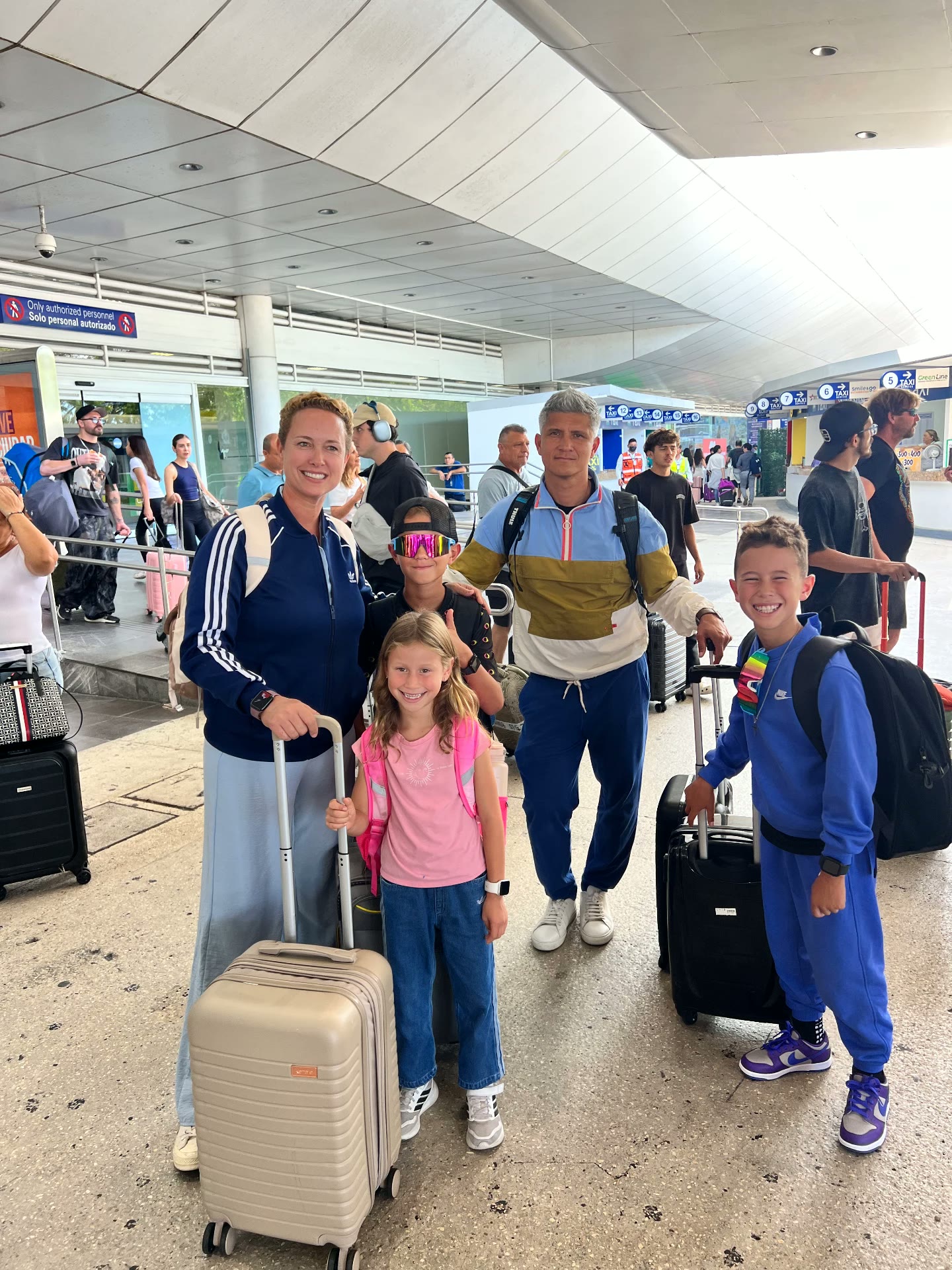 A family walking through an airport terminal with their bags