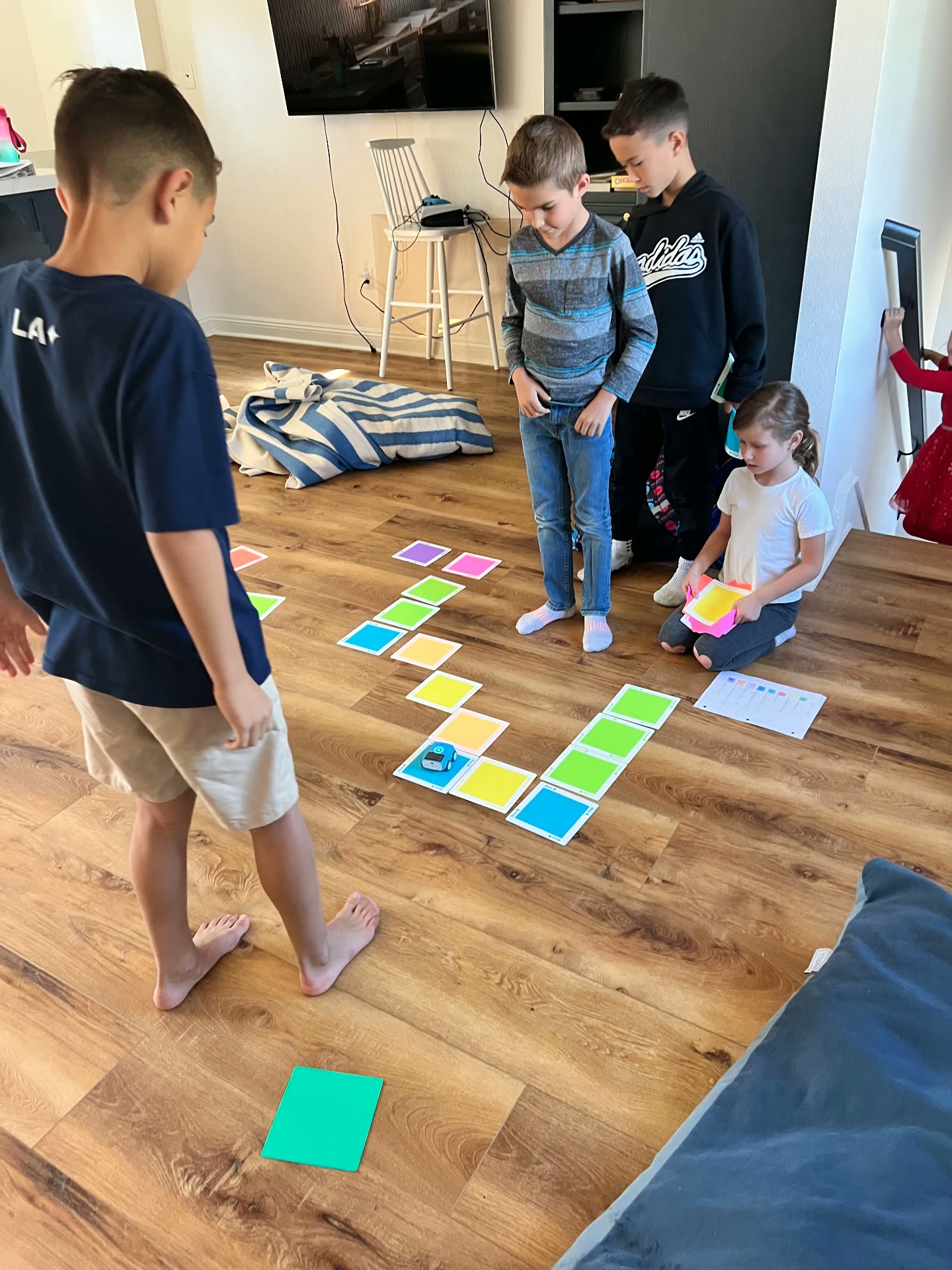 Children programming a small robot along a path of colored coding cards on the floor