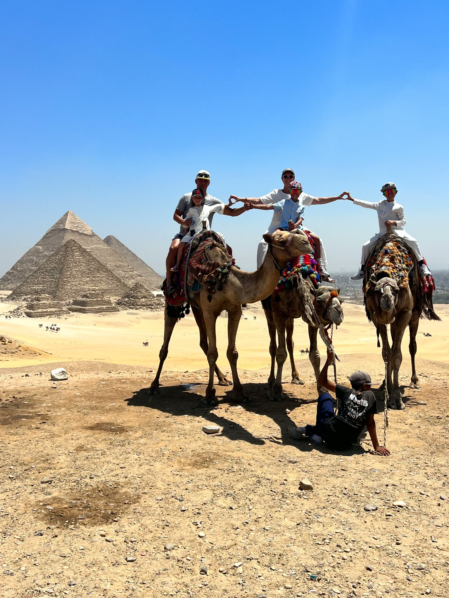 A family riding camels together in front of the pyramids of Giza
